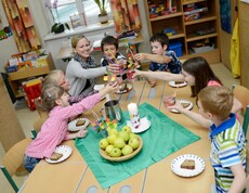 Kinder sitzen bei der Jause zusammen und prosten sich zu.