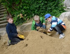 Drei Kinder beim Sandhaufenspielen