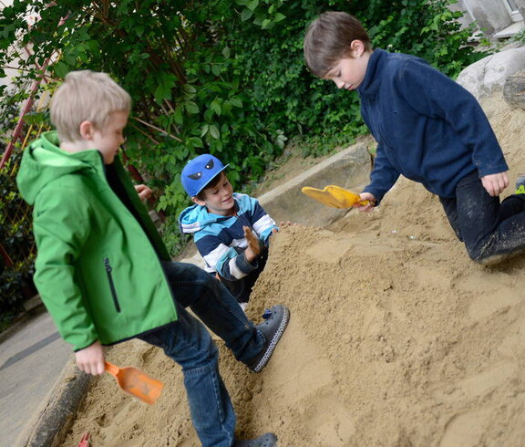 Drei Kinder beim Sandhaufenspielen