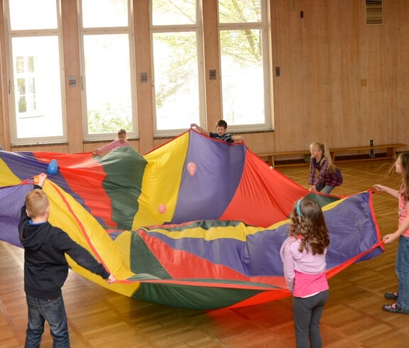 Kinder im Turnsaal mit einem Spieltuch