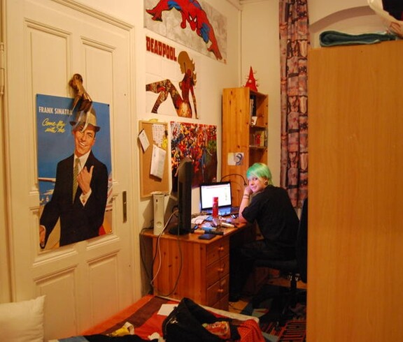 Eine Jugendliche sitzt in ihrem Zimmer am Schreibtisch.