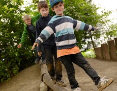 Drei Jungs balancieren über einen Holzbalken