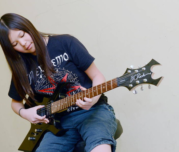 Ein Mädchen spielt auf einer E-Gitarre.