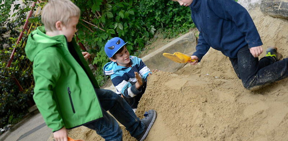 Drei Kinder beim Sandhaufenspielen
