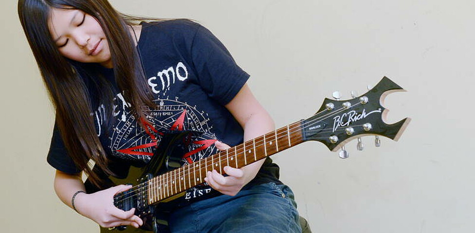 Ein Mädchen spielt auf einer E-Gitarre.