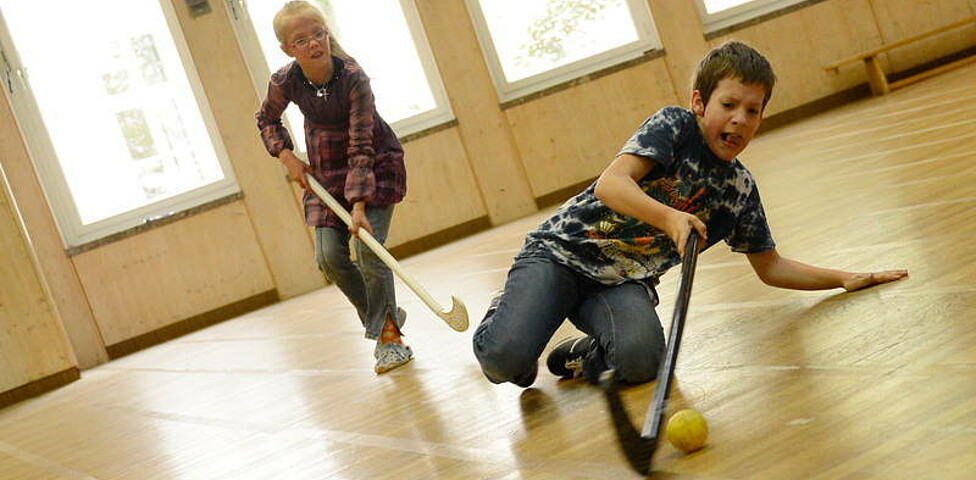 Kinder beim Hockeyspielen im Turnsaal